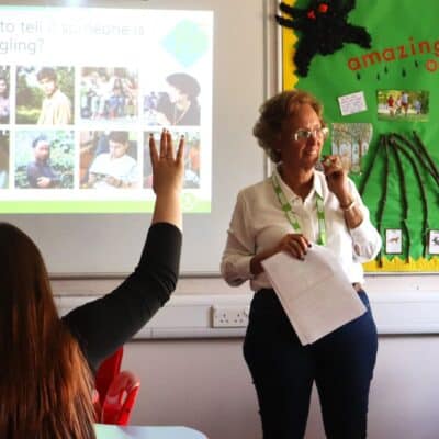 student putting hand up as facilitator stands in front of class