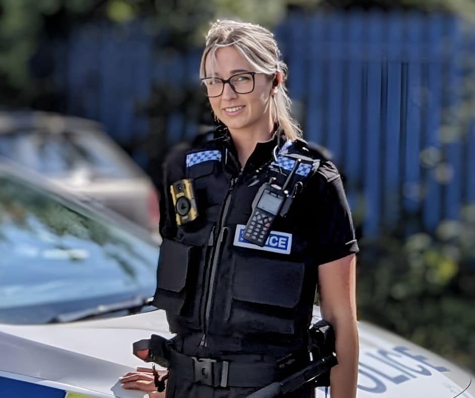 police officer standing in uniform in front of police car