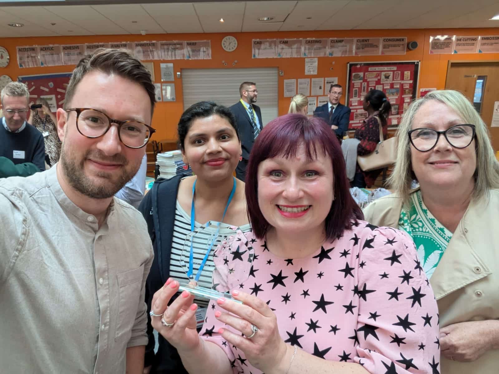 One male and three female staff take selfie with award