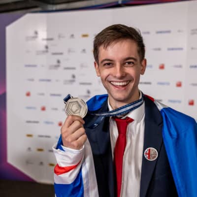 Harry holding up his silver medal with big smile on face