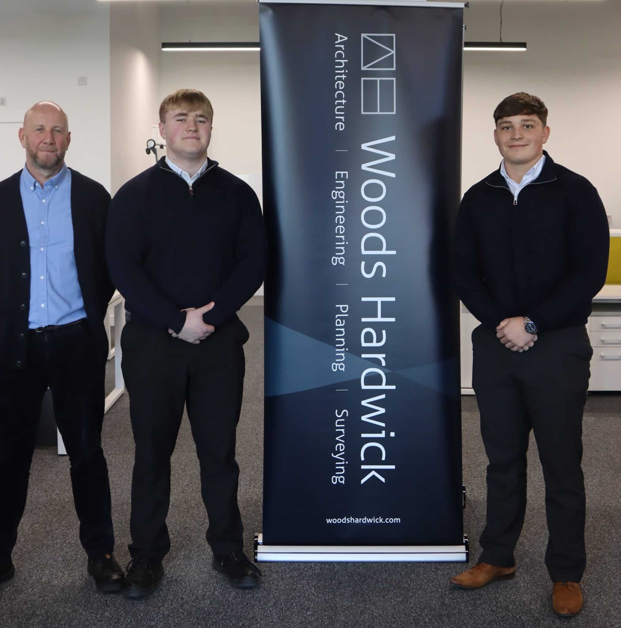 Matt Ford from Woods Hardwick with Scott and Jacob standing next to a banner