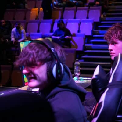 students sat at a computer, in a purple lighting playing esports games