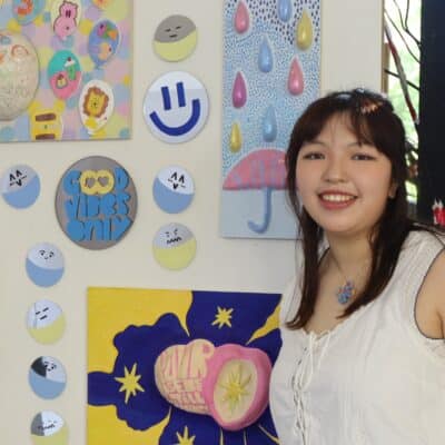 student standing in front of her artwork