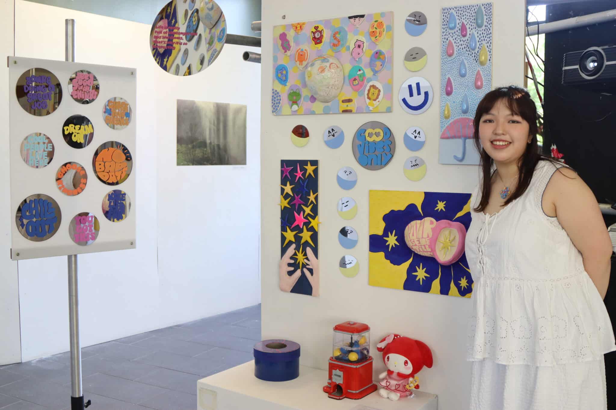 Student stands in front of their art piece