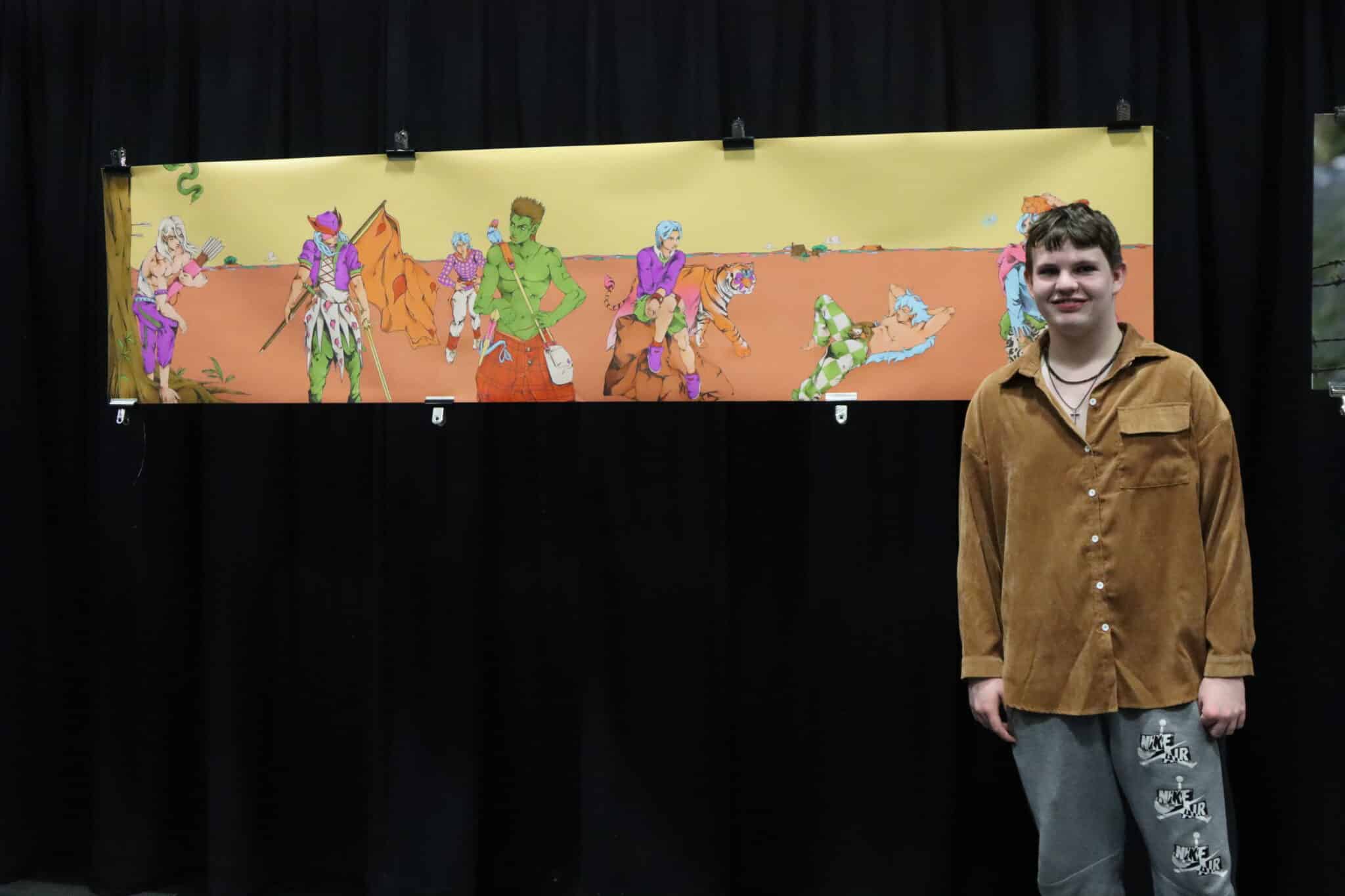 Creative students stand infront of their art pieces